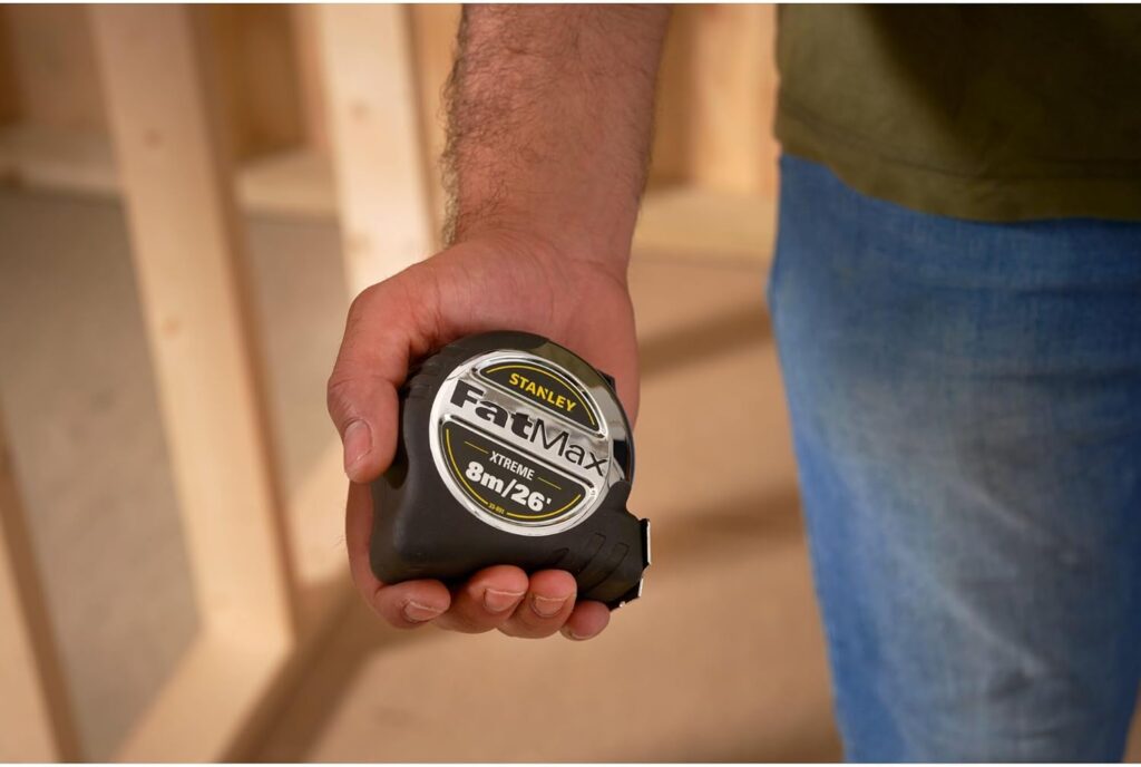 A carpenter holding a Stanley FatMax tape measure for carpentry